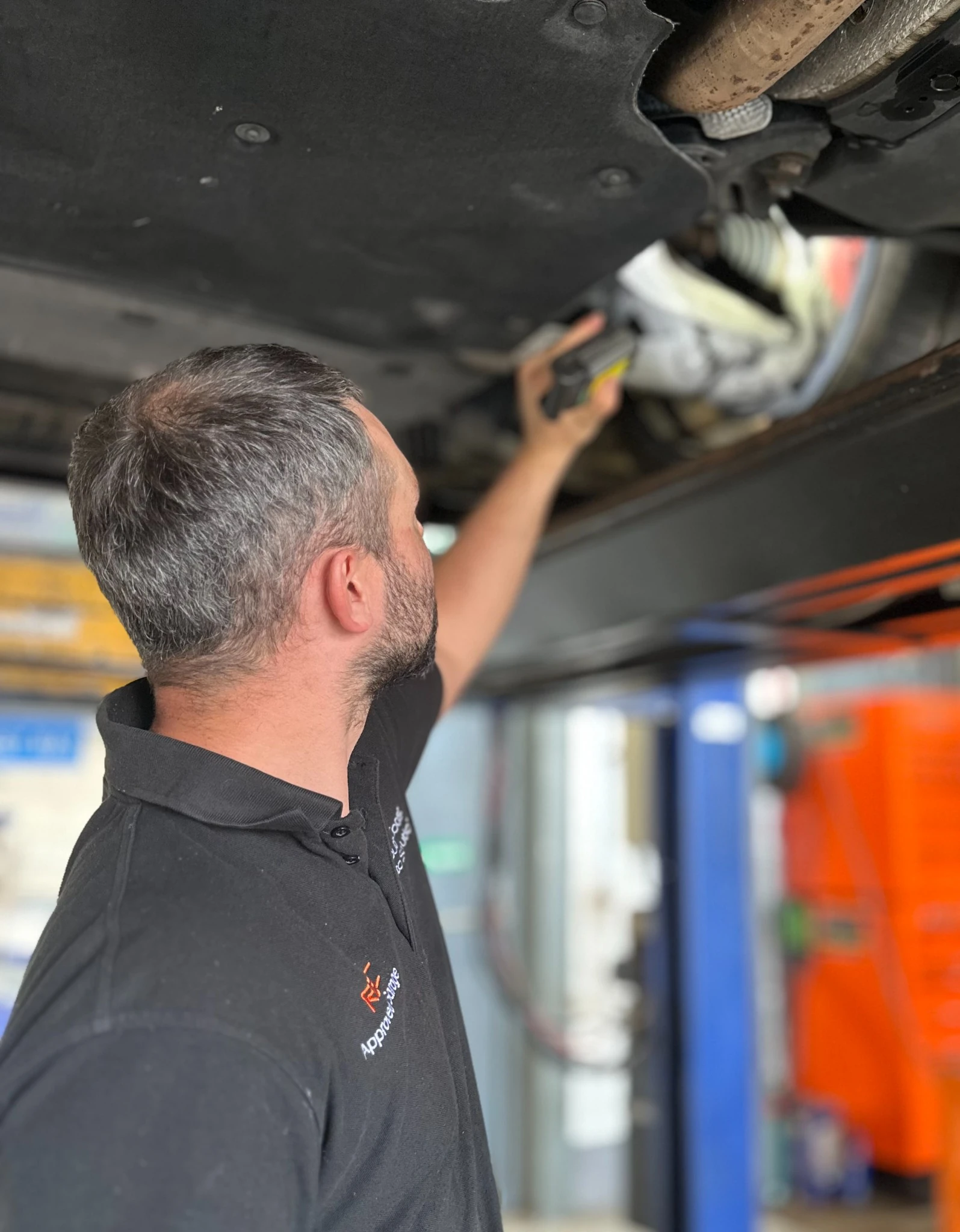 Technician inspecting a vehicle underside for MOT-related work